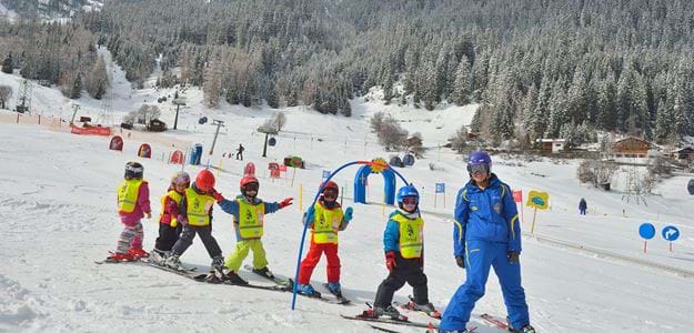 Glade børn på skiferien i børneområde på skiskole i St. Anton