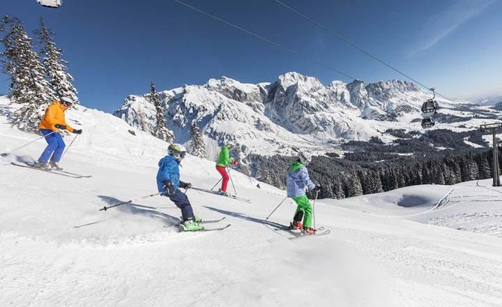 Familie med børn på ski i solskin på hvid piste med smuk udsigt i Val d'isere